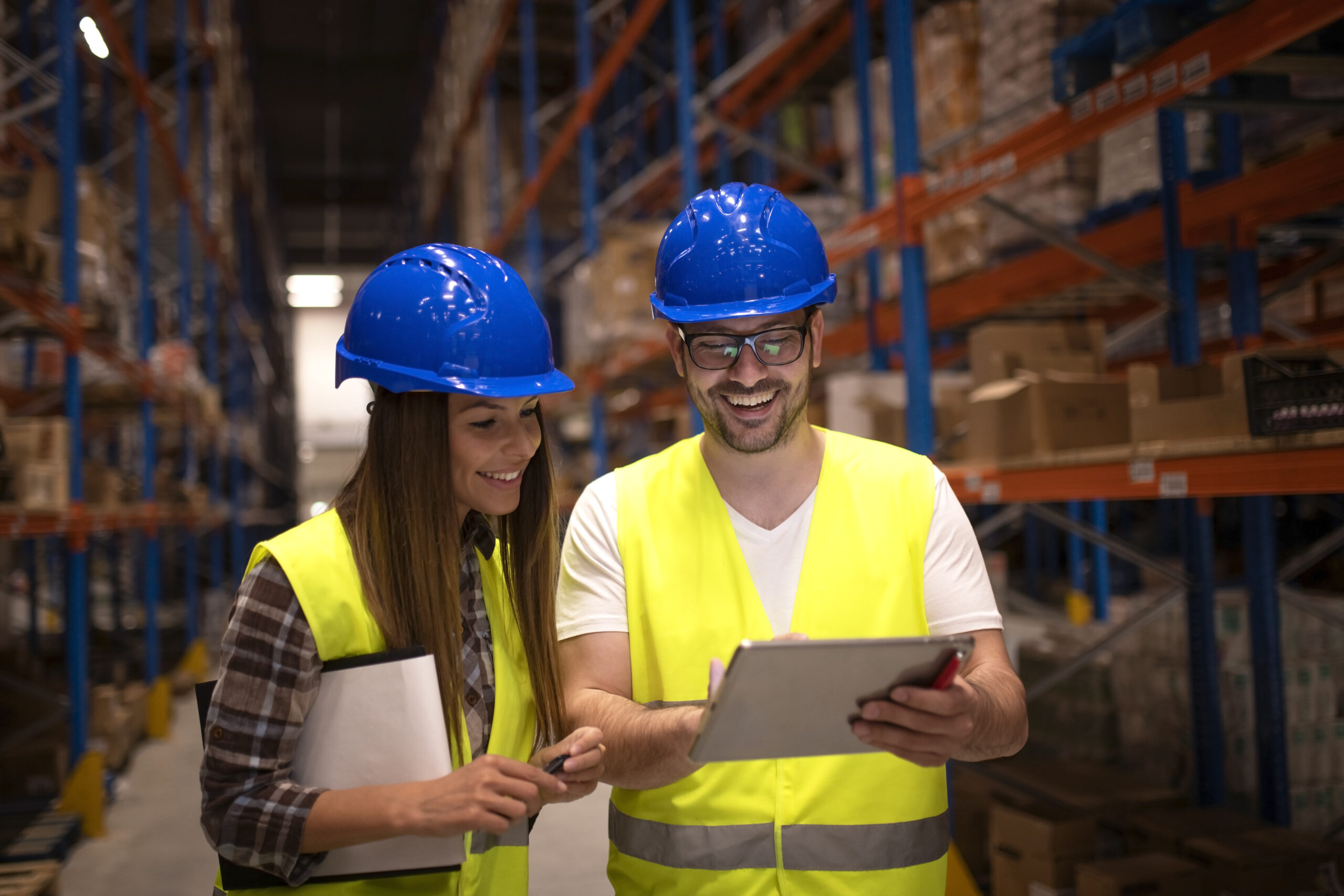 Warehouse workers checking shipment status on tablet computer.